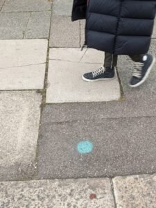 Green circle, spray-painted on pavement; feet walking by